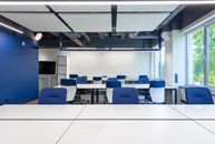 pexels-photo-6794970-6794970 Various white desks with blue chairs placed in modern spacious workspace with big window and monitor in contemporary business center